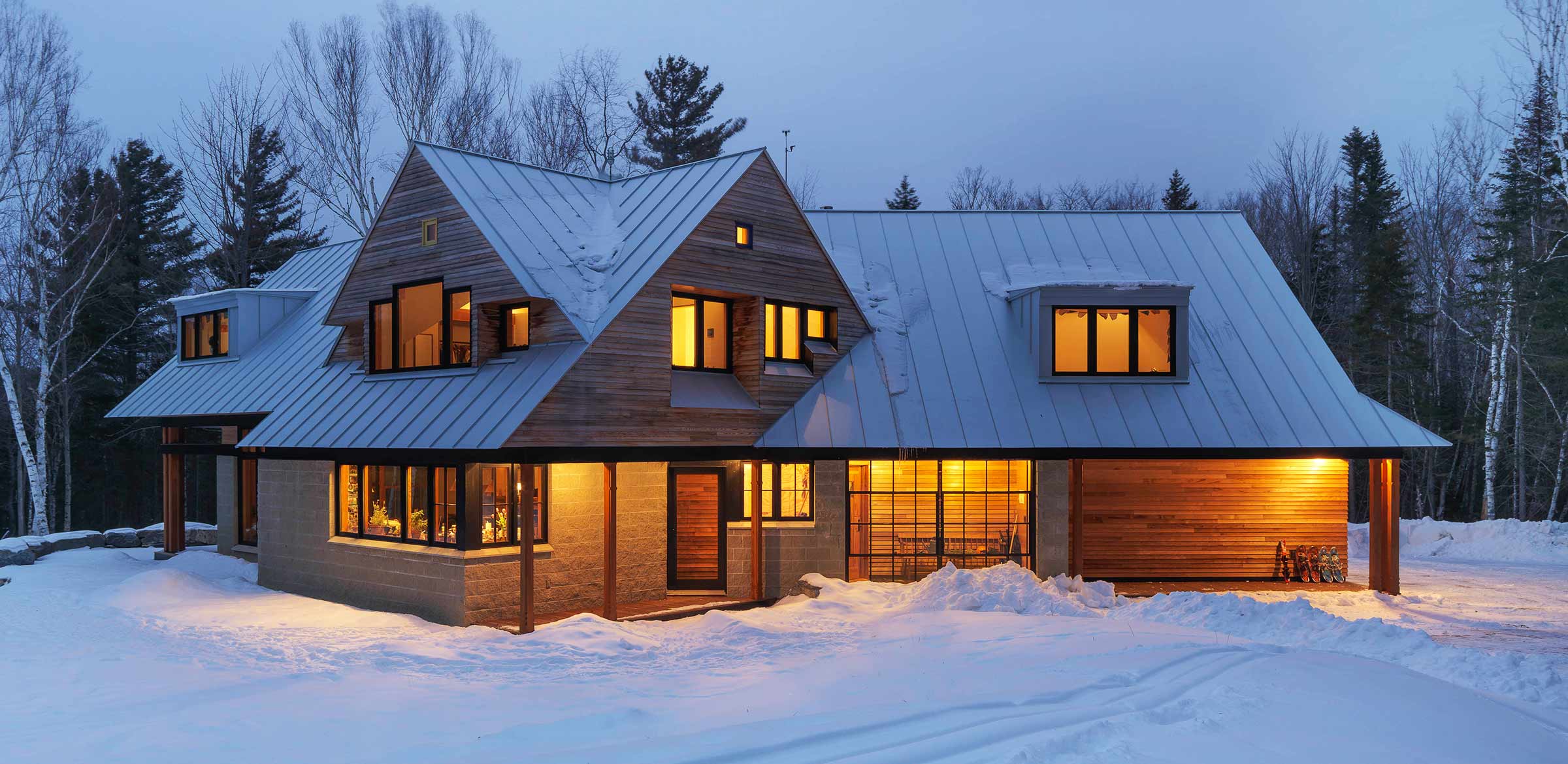 the house in the winter with warm lights and standing seam roof