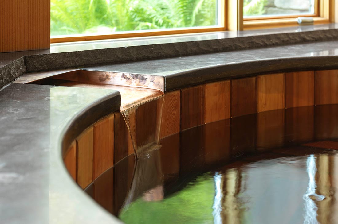 copper waterfall feature flowing into the tub